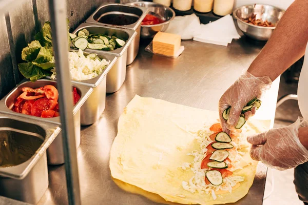 Vista recortada de cocinero en guantes preparación doner kebab - foto de stock