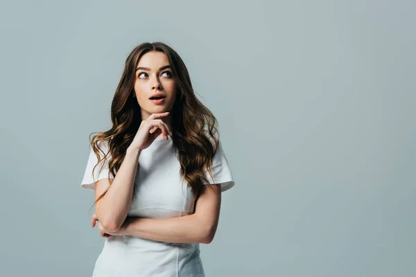 Hermosa chica con la boca abierta mirando hacia otro lado en camiseta blanca aislada en gris — Stock Photo