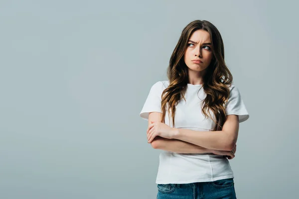 Upset beautiful girl in white t-shirt with crossed arms looking away isolated on grey — Stock Photo