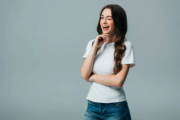 Menina bonita em branco t-shirt piscando com a boca aberta isolada em cinza — Fotografia de Stock