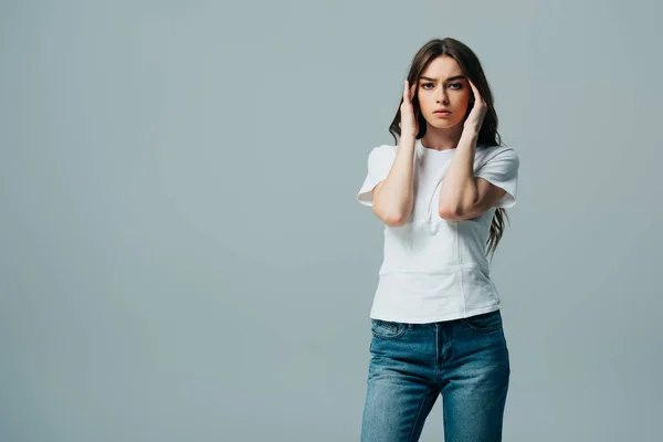 Tense beautiful girl in white t-shirt suffering from migraine isolated on grey — Stock Photo