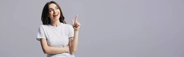 Menina bonita feliz em t-shirt branca mostrando gesto ideia e olhando para longe isolado em cinza, tiro panorâmico — Fotografia de Stock