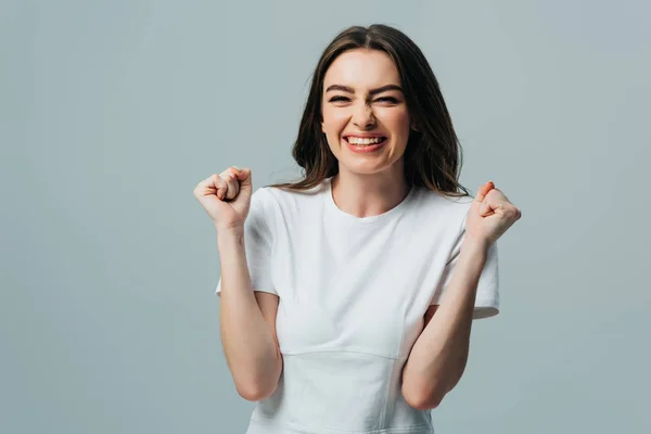 Excitada hermosa chica en camiseta blanca mostrando sí gesto aislado en gris - foto de stock