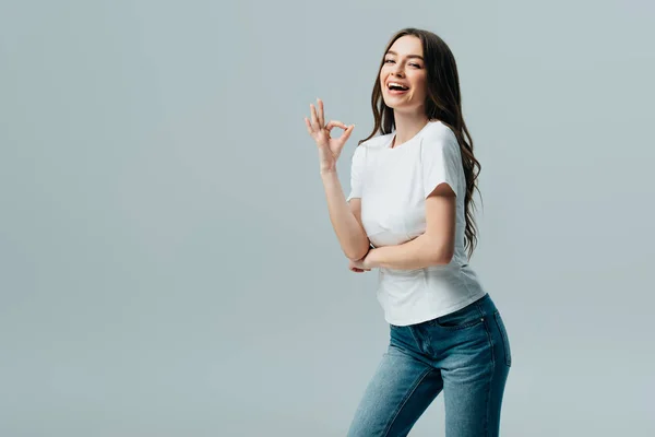 Beautiful girl in white t-shirt showing ok sign isolated on grey — Stock Photo