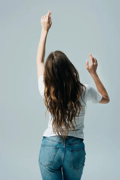 Rückansicht eines Mädchens in weißem T-Shirt und Jeans mit langen Haaren, das isoliert auf grau tanzt — Stockfoto