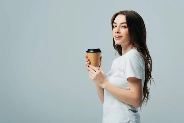 Side view of smiling beautiful girl in white t-shirt with paper cup isolated on grey — Stock Photo