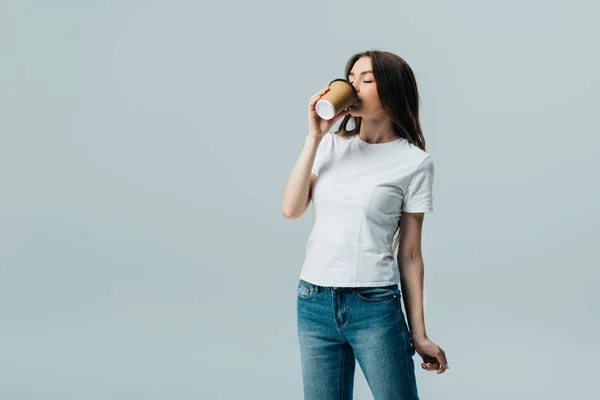 Schönes Mädchen im weißen T-Shirt mit geschlossenen Augen trinkt aus Pappbecher isoliert auf grau — Stockfoto