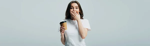 Surprised beautiful girl in white t-shirt with paper cup isolated on grey, panoramic shot — Stock Photo