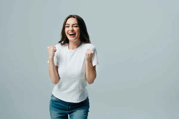 Excitado feliz hermosa chica en blanco camiseta mostrando sí gesto aislado en gris - foto de stock
