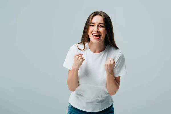 Feliz chica bonita en camiseta blanca mostrando sí gesto aislado en gris - foto de stock