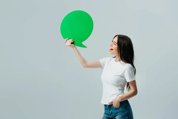 Happy beautiful girl in white t-shirt holding blank speech bubble isolated on grey — Stock Photo