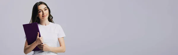 Menina bonita feliz em branco t-shirt segurando prancheta isolada em cinza, tiro panorâmico — Fotografia de Stock