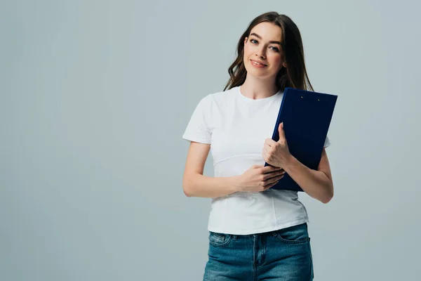 Happy beautiful girl in white t-shirt holding clipboard isolated on grey — Stock Photo