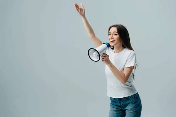 Alegre joven bonita mujer hablando en altavoz con la mano en el aire aislado en gris - foto de stock