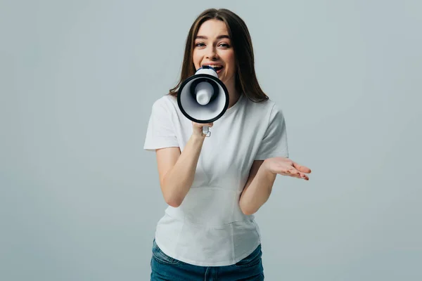 Молода красива жінка розмовляє в мегафоні ізольована на сірому — стокове фото
