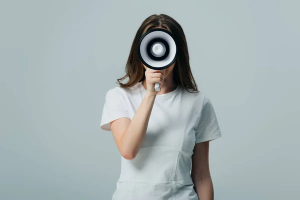 Young pretty woman holding loudspeaker in front of face isolated on grey — Stock Photo