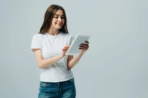 Glückliches Mädchen im weißen T-Shirt mit digitalem Tablet isoliert auf grau — Stockfoto