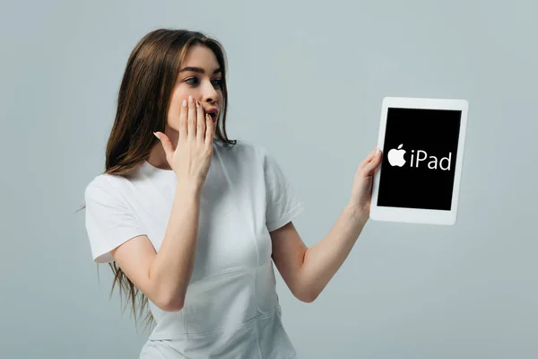 Київ, Україна-6 червня 2019: потрясла красива дівчина в Білій футболці показуючи цифровий планшет з логотипом iPad ізольований на сірому — стокове фото