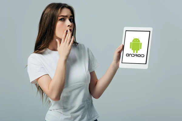 KYIV, UKRAINE - JUNE 6, 2019: shocked beautiful girl in white t-shirt showing digital tablet with android logo isolated on grey — Stock Photo