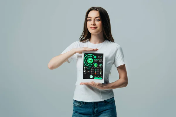 Smiling beautiful girl in white t-shirt showing digital tablet with infographics app isolated on grey — Stock Photo