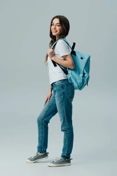 Vue pleine longueur de jolie fille souriante avec sac à dos bleu isolé sur gris — Photo de stock