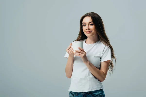 Smiling girl in white t-shirt holding white mug isolated on grey — Stock Photo