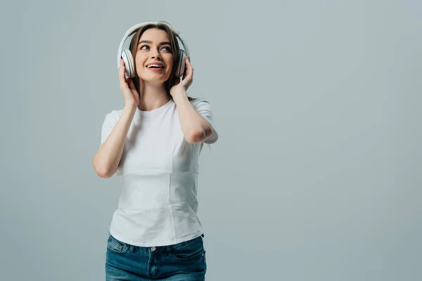 Chica soñadora feliz escuchando música en auriculares inalámbricos aislados en gris — Stock Photo
