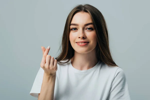 Beautiful smiling girl showing money gesture isolated on grey — Stock Photo