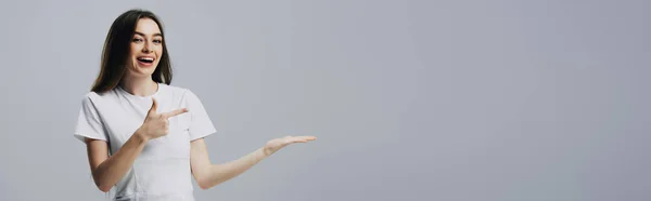 Heureux jolie fille pointant avec doigt et main isolé sur gris, panoramique shot — Photo de stock