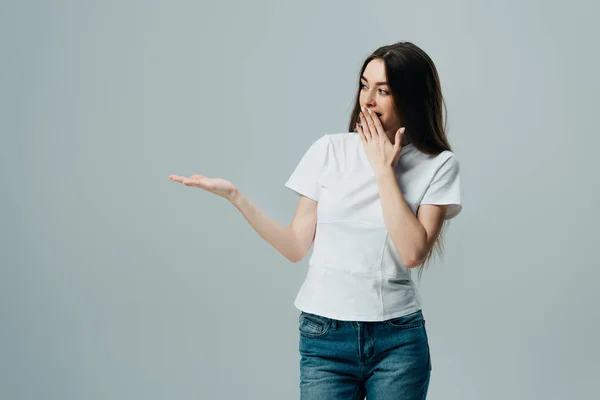 Schöne glückliche überraschte Mädchen zeigt mit der Hand isoliert auf grau — Stock Photo