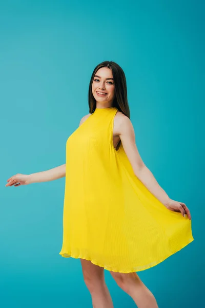 Glücklich lächelnd schönes Mädchen in gelbem Kleid isoliert auf Türkis — Stockfoto