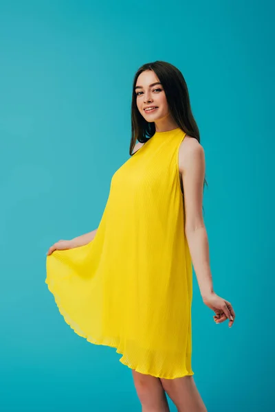 Happy beautiful girl in yellow dress isolated on turquoise — Stock Photo