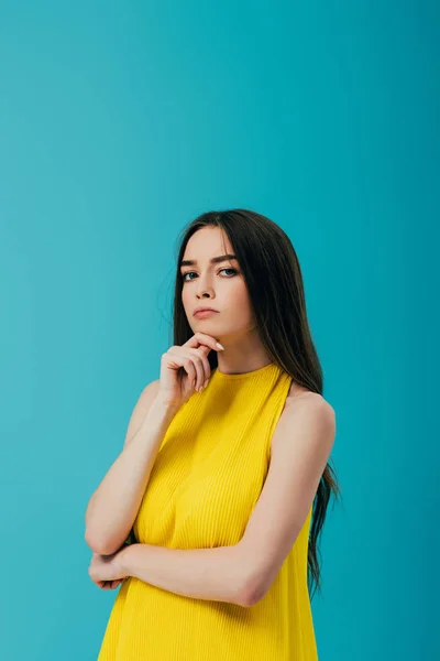 Pensativo hermosa chica en vestido amarillo mirando cámara aislada en turquesa - foto de stock