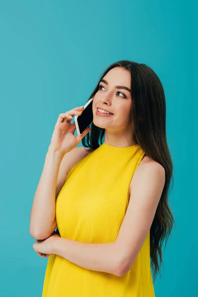 Sonhador menina bonita em vestido amarelo falando no smartphone isolado em turquesa — Fotografia de Stock