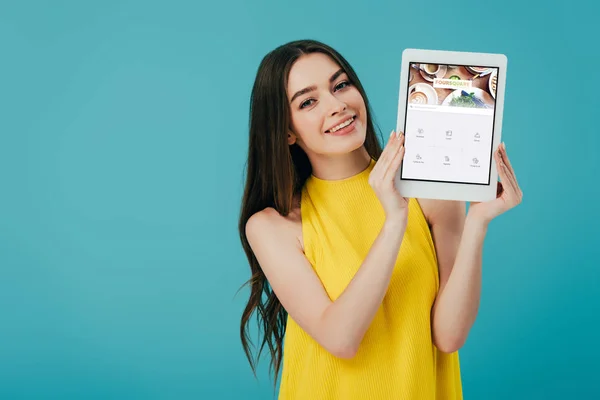 Київ, Україна-6 червня 2019: щасливий красива дівчина в жовтій сукні показує цифровий планшет з додатком forsquare, ізольованих на бірюзові — стокове фото