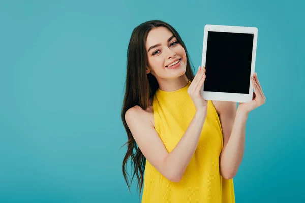 Belle fille souriante en robe jaune montrant tablette numérique avec écran blanc isolé sur turquoise — Photo de stock
