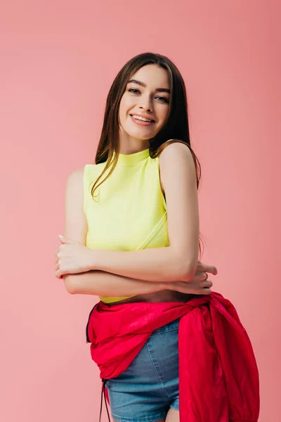 Bela menina sorridente em roupas brilhantes com braços cruzados isolado em rosa — Fotografia de Stock