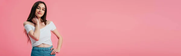 Bella ragazza sorridente posa con mano sul fianco isolato su rosa, colpo panoramico — Foto stock