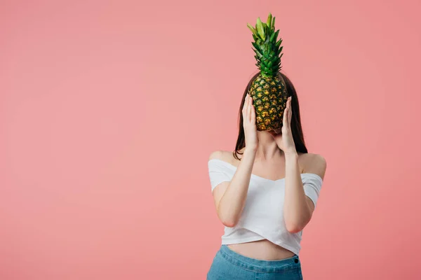 Girl holding ripe delicious pineapple in front of face isolated on pink — Stock Photo