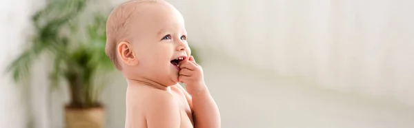 Plan panoramique de mignon petit enfant souriant et prenant la main dans la bouche — Photo de stock