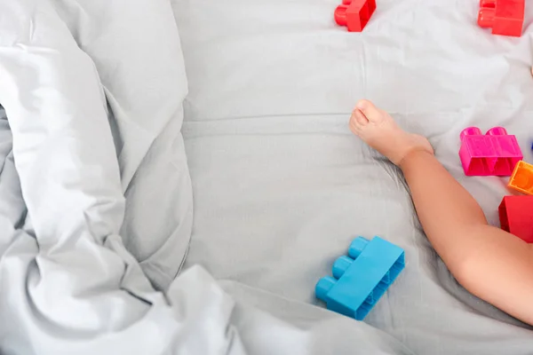 Частковий вигляд босоніж дитячої ноги на ліжку біля барвистої конструкції — стокове фото