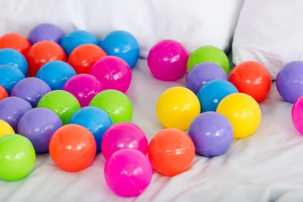 Яркие разноцветные игрушечные шарики, разбросанные по белым простыням — стоковое фото