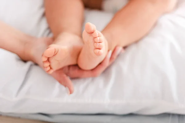 Vista cortada da mãe tocando pequenas pernas de bebê descalças — Fotografia de Stock
