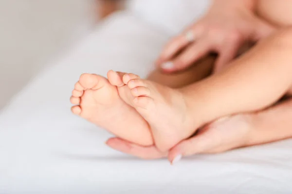 Vista recortada de la mujer tocando las piernas de la hija bebé - foto de stock