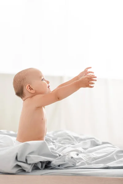 Vue latérale de mignon petit enfant en couches souriant et levant les mains vers le haut — Photo de stock