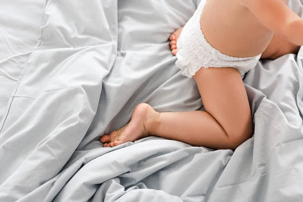 Vista cortada do bebê bonito na fralda que kneeing no cobertor branco — Fotografia de Stock