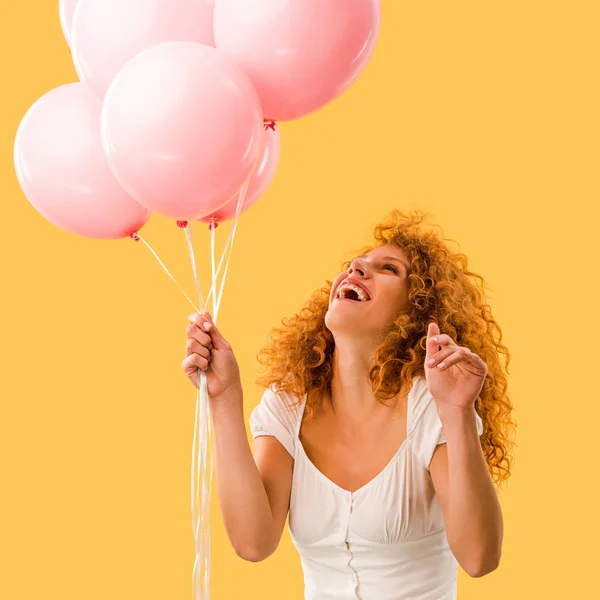 Animado bela ruiva mulher com balões rosa isolado no amarelo — Fotografia de Stock