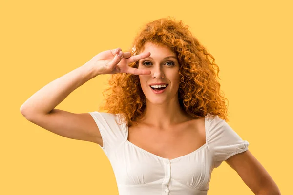 Glückliche Frau mit roten Haaren mit Friedenssymbol auf gelbem Hintergrund — Stockfoto