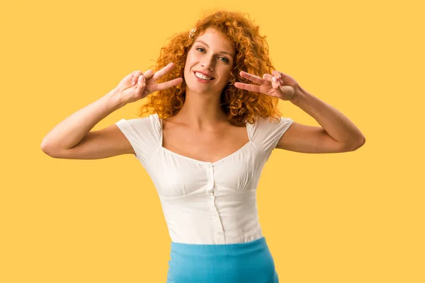 Весела жінка з рудим волоссям, що показує символи миру ізольовані на жовтому — стокове фото