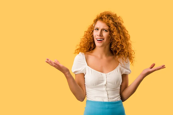 Confused redhead woman with shrug gesture, isolated on yellow — Stock Photo